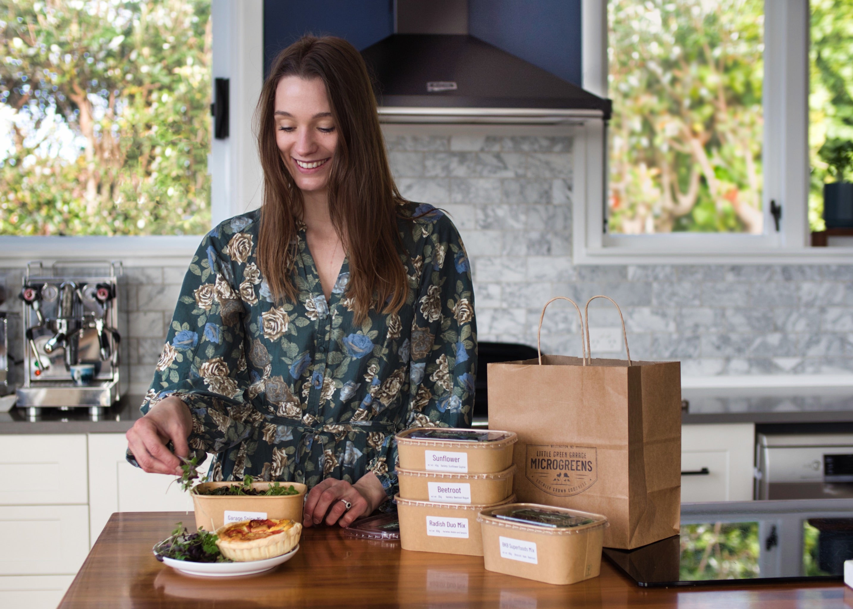 A woman in a modern home kitchen adding microgreens to her plate.